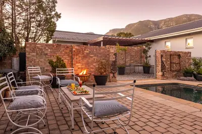 a patio with chairs and a table next to a pool at 55 MainStay in Hermanus