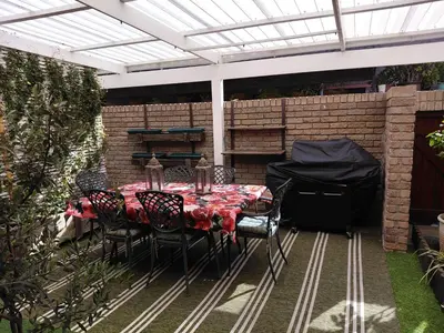 a patio with a table and chairs under a pergola at Blouberg Beach Villa in Cape Town