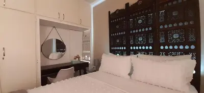 a bedroom with a white bed with a black headboard and a mirror at Blouberg Beach Villa in Cape Town