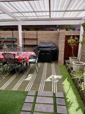 a patio with a table and a white pergola at Blouberg Beach Villa in Cape Town