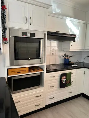 a kitchen with white cabinets and a microwave at Blouberg Beach Villa in Cape Town