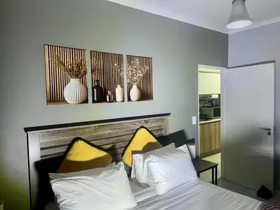 a bedroom with a bed with two yellow pillows at The CoziPlace One in Cape Town