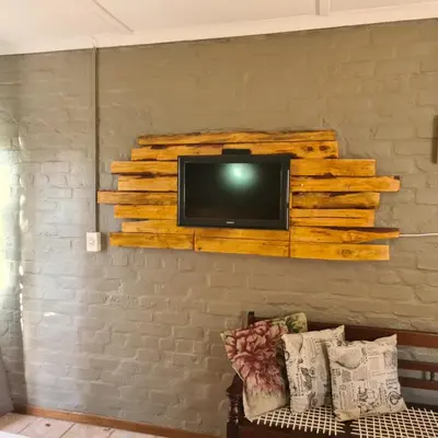 a tv mounted on a wall with a wooden shelf at Mads Place in Cape Town