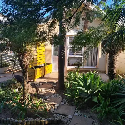 a yellow house with trees and plants in front of it at Mads Place in Cape Town
