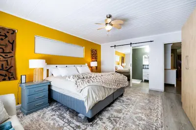 a bedroom with a bed and a yellow wall at Florie se Huis in Paarl