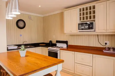 a kitchen with white cabinets and a wooden table at Skilpadvlei Wine Farm in Stellenbosch