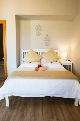 a large white bed with a stuffed animal on it at Skilpadvlei Wine Farm in Stellenbosch