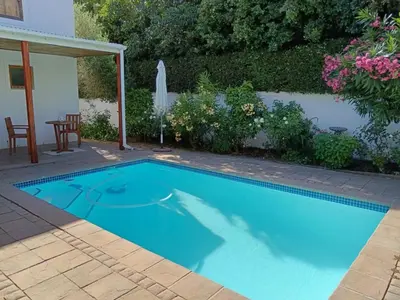 a swimming pool in a yard with a table and chairs at d'Vine Maison in Franschhoek