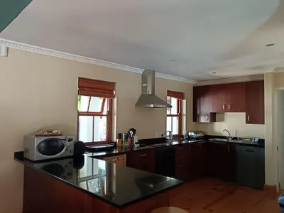 a kitchen with wooden cabinets and a black counter top at d'Vine Maison in Franschhoek