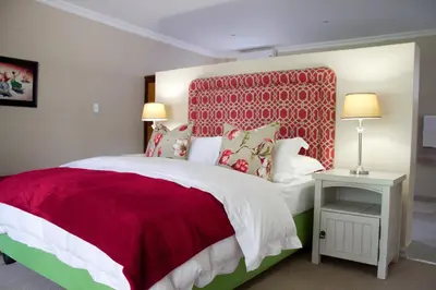 a bedroom with a large bed with a red headboard at Nuwerus Lodge Paarl in Paarl