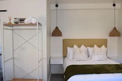 a bedroom with a bed with white sheets and pillows at House on Pringle in Cape Town