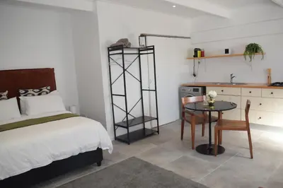 a bedroom with a bed and a table and a kitchen at House on Pringle in Cape Town