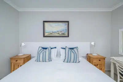 a bedroom with a white bed with blue pillows at Island view on Clam in Cape Town