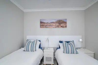 two beds in a room with white walls at Island view on Clam in Cape Town