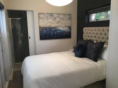 a bedroom with a white bed and a painting on the wall at Lovely studio apartment in Pinelands, Cape Town in Cape Town