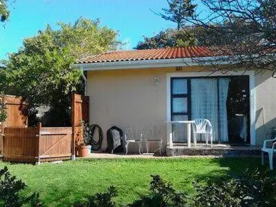 a house with two chairs and a yard with a house at Cosy studio garden cottage in Cape Town