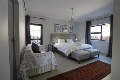 a bedroom with a bed and a chair and window at At Hummingbird Hill Hermanus in Hermanus