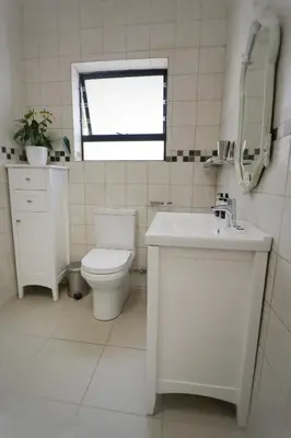 a white bathroom with a toilet and a sink at At Hummingbird Hill Hermanus in Hermanus