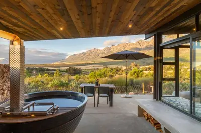a bathroom with a tub and a table with an umbrella at Steenbok farm cottages Sunbird Cottage in Wolseley