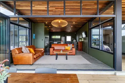 an open living room with orange couches and a table at Steenbok farm cottages Kingfisher Cottage in Wolseley