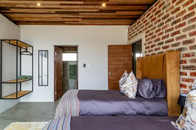 a bedroom with a bed and a brick wall at Steenbok farm cottages Kingfisher Cottage in Wolseley