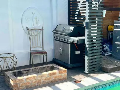 a grill and a chair sitting next to a pool at Apartment on 32 in Cape Town