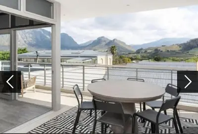 a balcony with a table and chairs and mountains at Franschhoek - La Petit Village - Views in Franschhoek