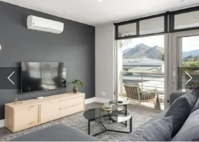 a living room with a couch and a flat screen tv at Franschhoek - La Petit Village - Views in Franschhoek