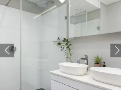 a white bathroom with two sinks and a shower at Franschhoek - La Petit Village - Views in Franschhoek