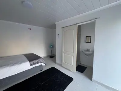 a bedroom with a bed and a bathroom with a sink at No 1 Guest house in Cape Town