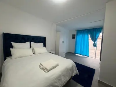 a bedroom with a large white bed with a blue headboard at No 1 Guest house in Cape Town