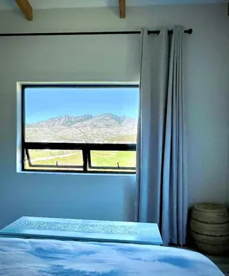 a bedroom with a window with a mountain view at Prinia on Peak in Pringle Bay in Pringle Bay
