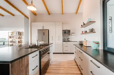 a kitchen with white cabinets and black counter tops at Prinia on Peak in Pringle Bay in Pringle Bay