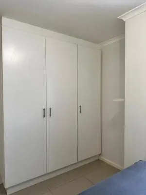 a white bedroom with white cabinets and a bed at Cozy Rondebosch Apartment in Cape Town