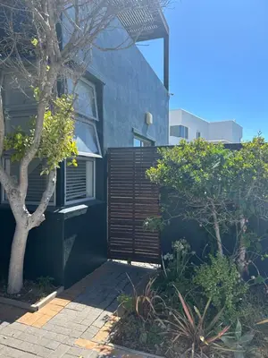 a blue house with a fence and a tree at Sunset Studio Garden View in Cape Town