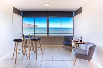 a room with a table and chairs and a large window at Isla's Place (Strandsig 304) in Cape Town