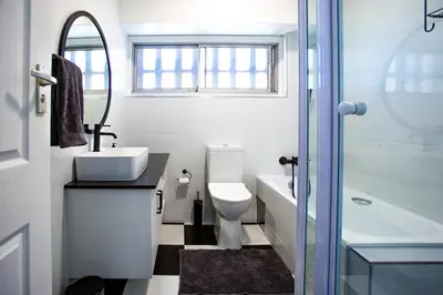 a bathroom with a sink and a toilet and a mirror at Isla's Place (Strandsig 304) in Cape Town