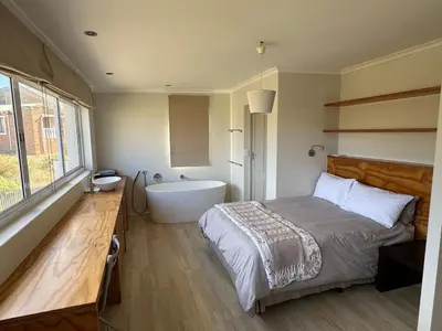 a bedroom with a bed and a bath tub at Die Steenhuisie in Pringle Bay