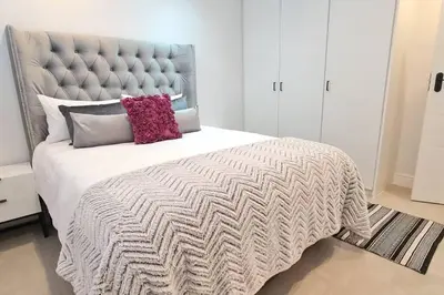 a bedroom with a large bed with a gray headboard at Villa Lamsyh- your second home in Cape Town
