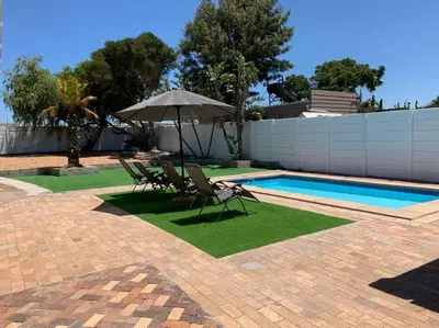 two chairs and an umbrella next to a swimming pool at Villa Lamsyh- your second home in Cape Town