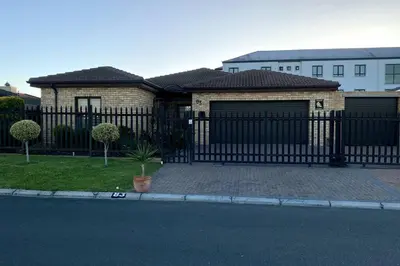 a house with a black wrought iron fence at Bosch Villa in Cape Town