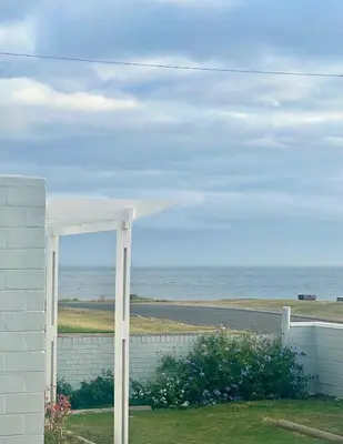 a white building with a view of the ocean at Brunia Bay Apartment in Hermanus