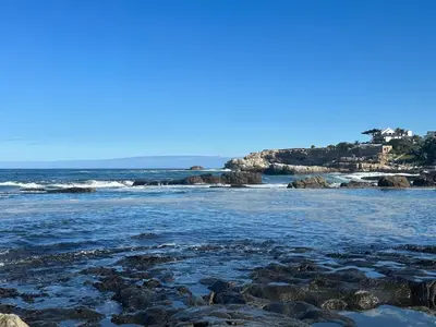 a beach with rocks and the ocean on a clear day at Brunia Bay Apartment in Hermanus