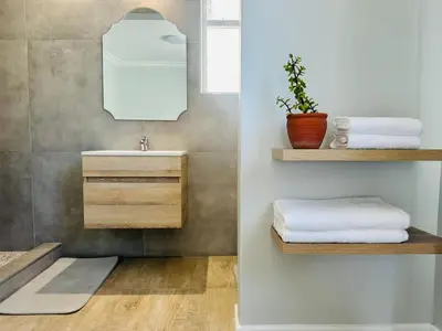 a bathroom with a sink and a mirror and towels at Brunia Bay Apartment in Hermanus