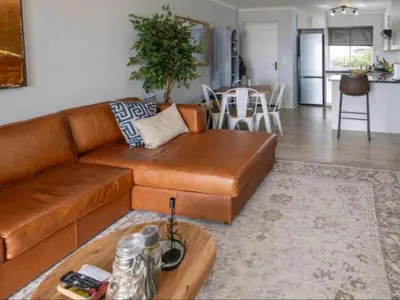 a brown leather couch in a living room with a table at Refresh at 50 Whale Rock in Hermanus