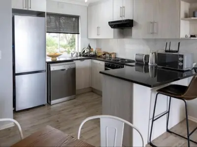 a kitchen with white cabinets and stainless steel appliances at Refresh at 50 Whale Rock in Hermanus