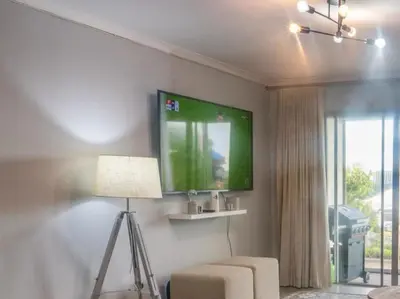a living room with a tv on the wall at Refresh at 50 Whale Rock in Hermanus