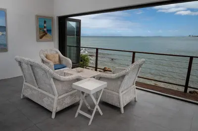 a balcony with chairs and a table and a view of the ocean at 'Seagul Cove', Private Villa on the beach, Sleeps 7 in Cape Town