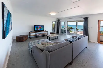 a living room with a couch and a television at 'Seaside Cottage', Sleeps 4 with a 3 minute walk from the beach! in Cape Town