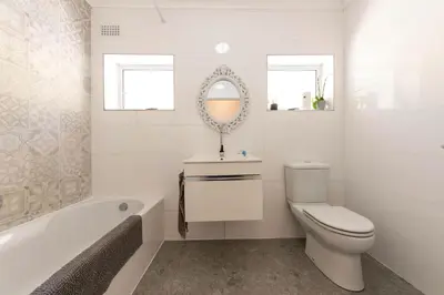 a bathroom with a toilet and a sink and a tub at 'Seaside Cottage', Sleeps 4 with a 3 minute walk from the beach! in Cape Town